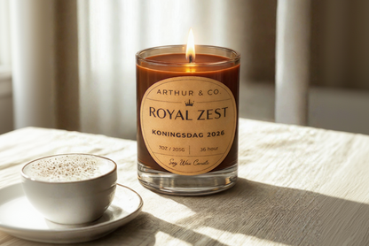Candle labeled 'Royal Zest' by Arthur & Co. on a table with a cup of coffee.