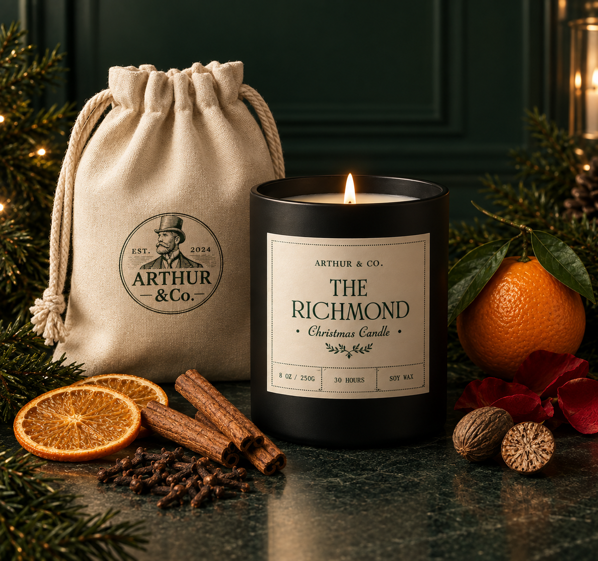A black candle jar labeled 'Arthur & Co. The Richmond Christmas Candle' stands lit beside a beige drawstring pouch with the same brand logo.